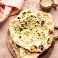 [Handcrafted from a delicate mixture of wheat flour, yogurt, and leavening agents, Butter Naan is expertly stretched, then baked in a traditional tandoor (clay oven) to achieve its signature texture. What sets it apart is the heavenly touch of clarified butter (ghee) brushed generously on its warm surface, imparting a luxurious richness and a glossy finish] Butter Naan